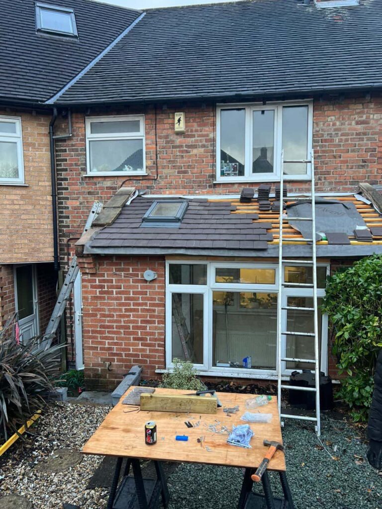 This is a photo of a roof extension that is having new roof tiles installed. This is a photo taken from the roof ridge looking down a tiled pitched roof on to a flat roof. Works carried out by Soham Roofing Repairs