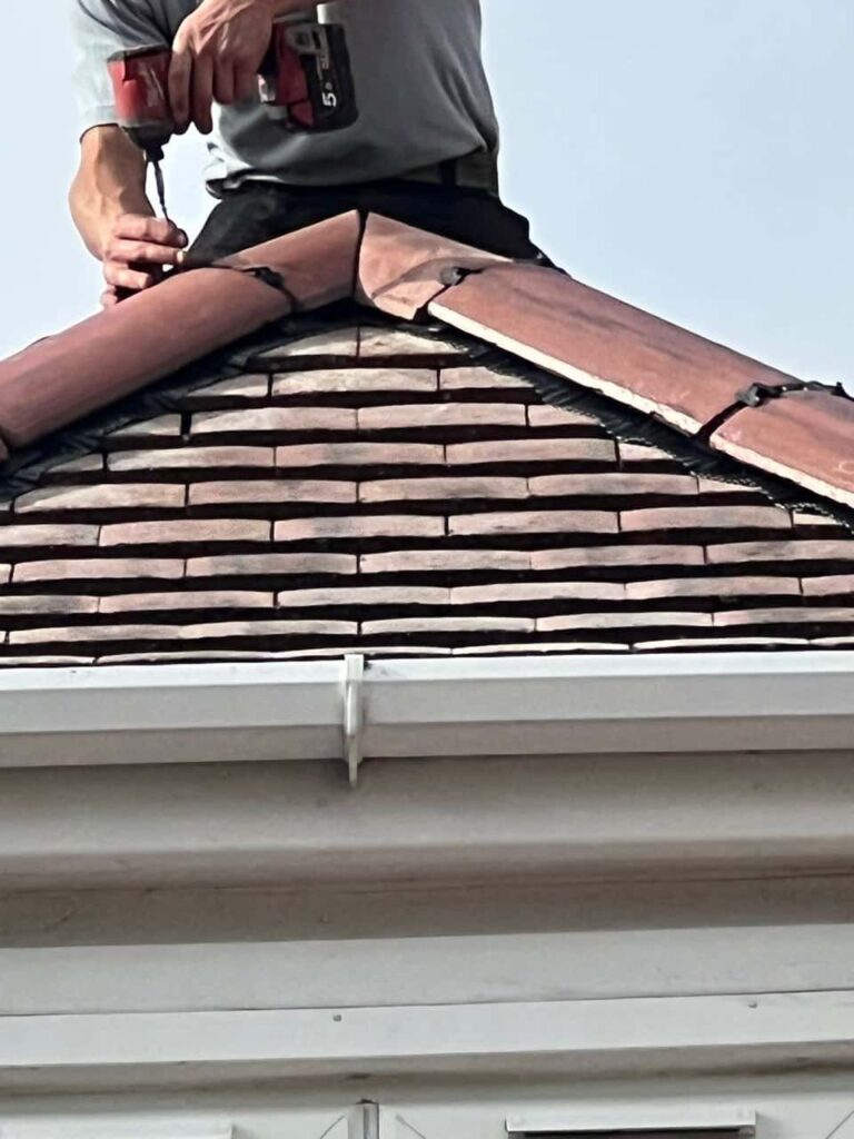 This is a photo of one of the operatives of Soham Roofing Repairs installing new ridge tiles